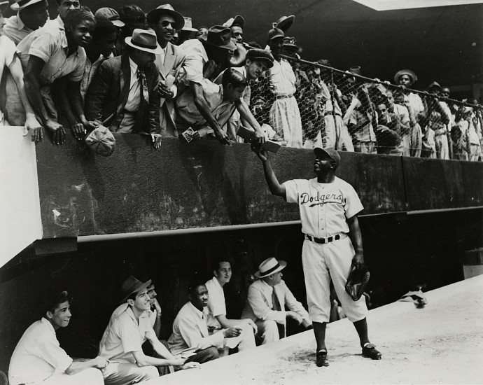 Unidentified photographer, Jackie Robinson returns an autograph to a fan in the stands. Dodgers' spring training in Cuidad Trujillo (now Santo Domingo), Dominican Republic, March 6, 1948
Gelatin silver print; printed later, 7 7/16 x 9 3/8 in. (18.9 x 23.8 cm)
Probably printed from a copy negative.
Annotated [incorrectly] "Jackie Robinson at Ebbett's Field" in ink with printing percentages and other annotations in red on print verso.
Illustrated: The St. Louis Star and Times,  March 8, 1948. 
8503